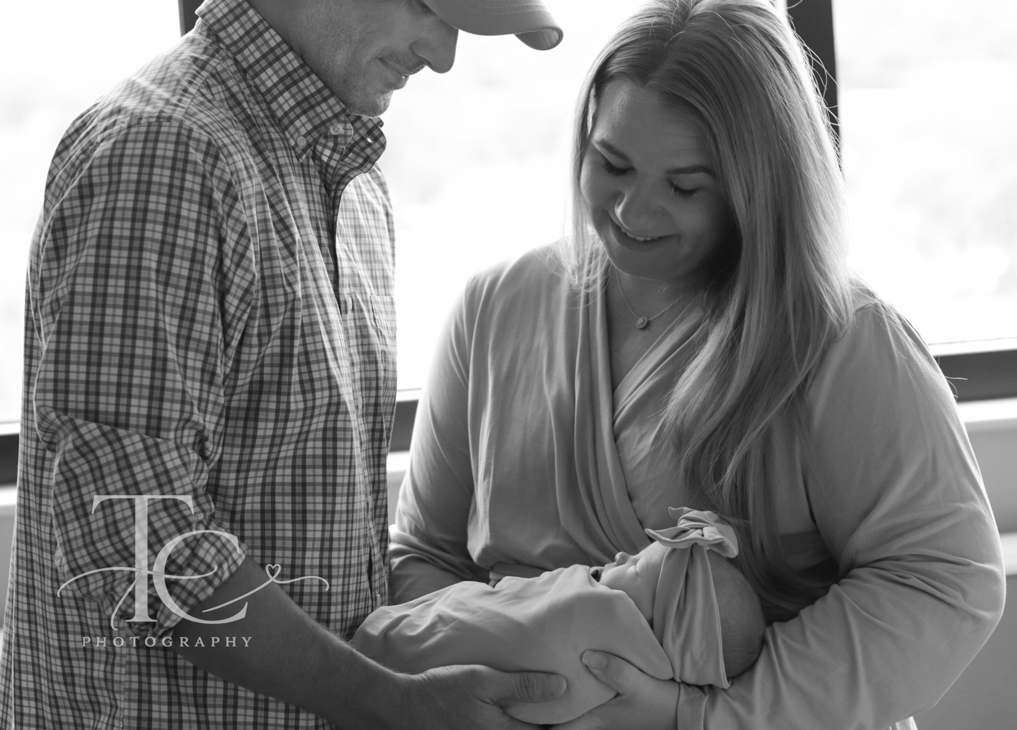 Black-and-white portrait of parents looking at their newborn
