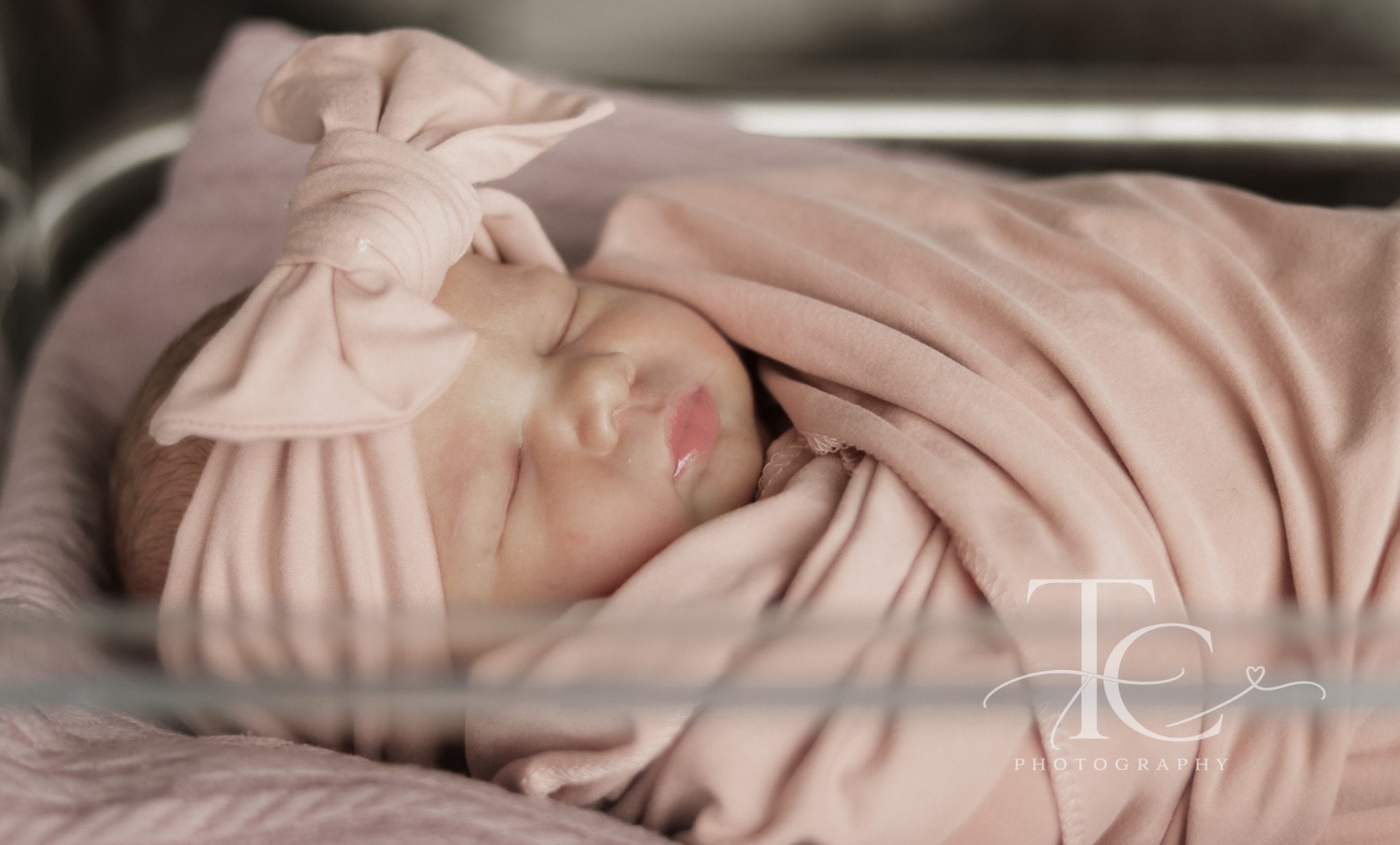 Close-up of a sleeping newborn in a pink bow hat
