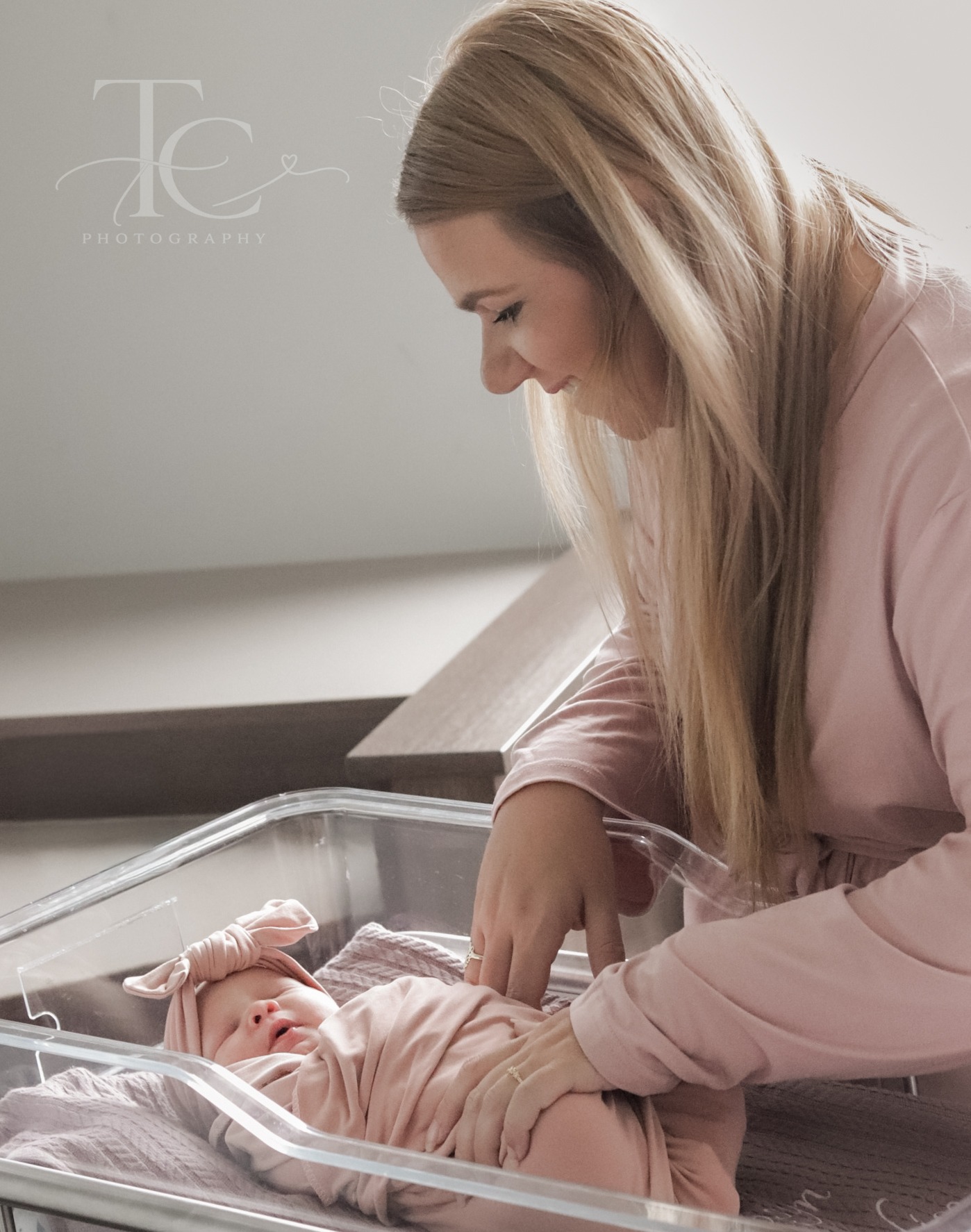 Mother gently touching her newborn in the bassinet