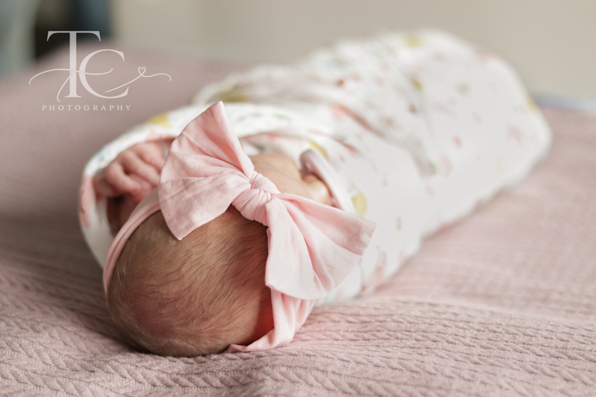 Overhead view of a newborn wrapped in floral fabric with a pink bow