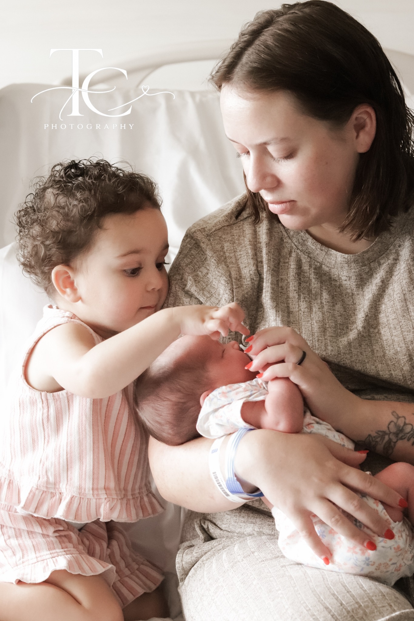 Older sibling gently touching newborn beside mother