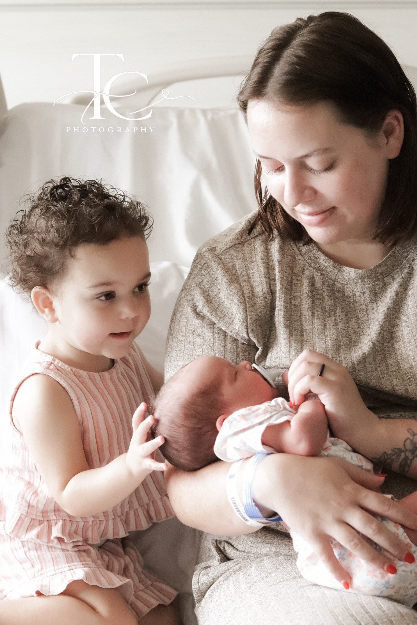 Mother smiling as older sibling meets newborn