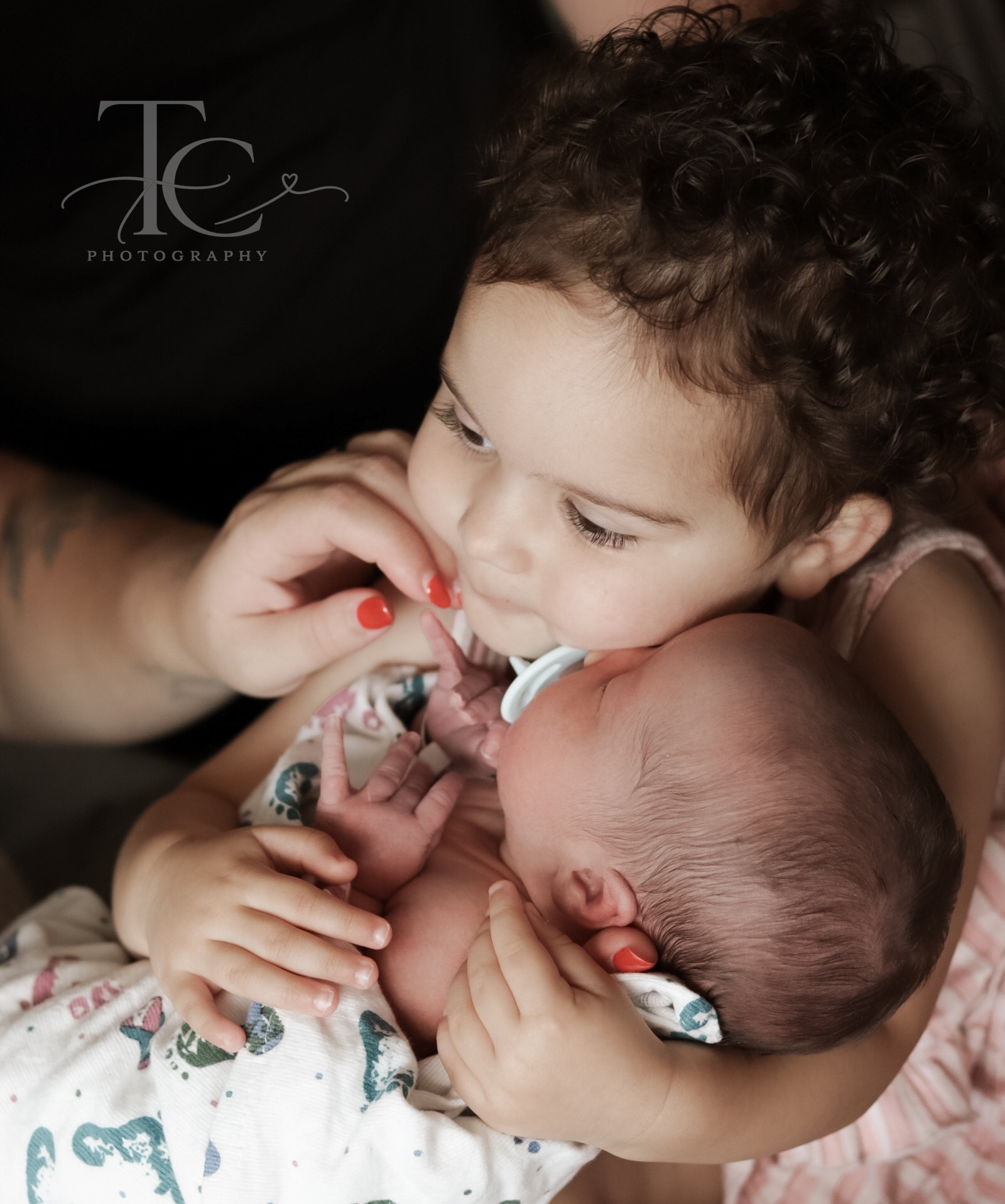 Older sibling gently kissing newborn