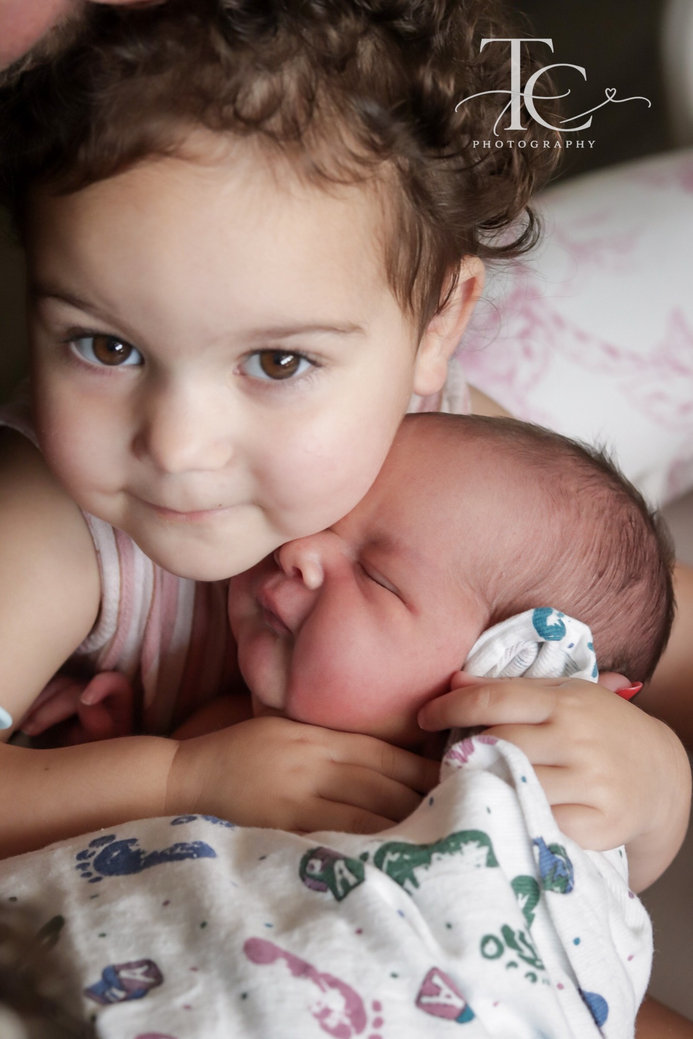 Older sibling cuddling beside newborn