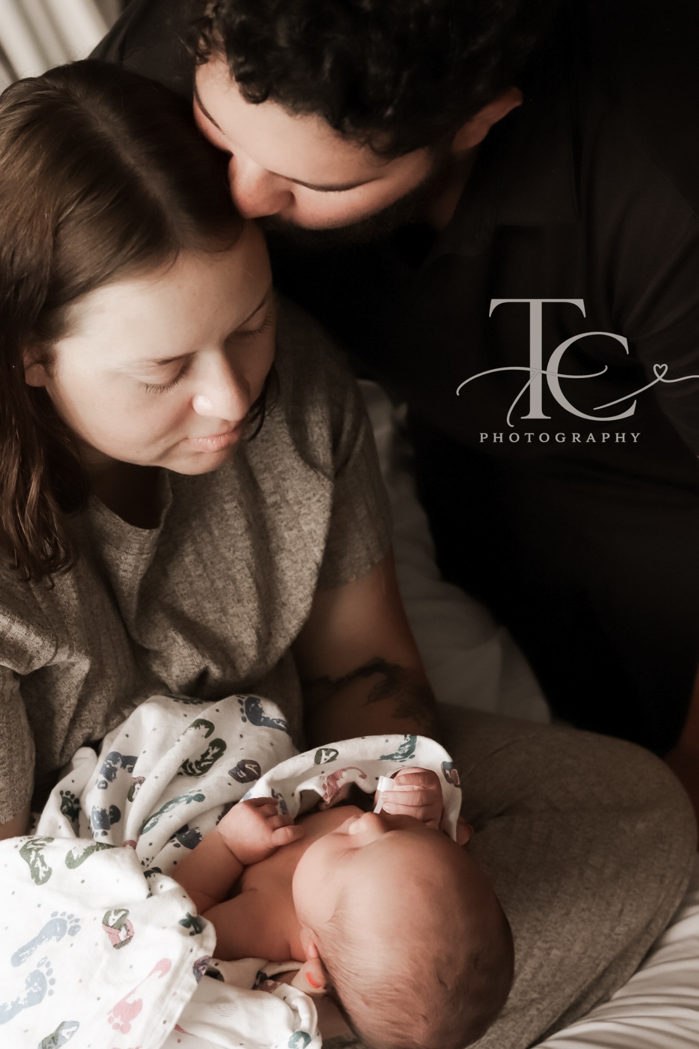 Father kissing mother as she holds their newborn