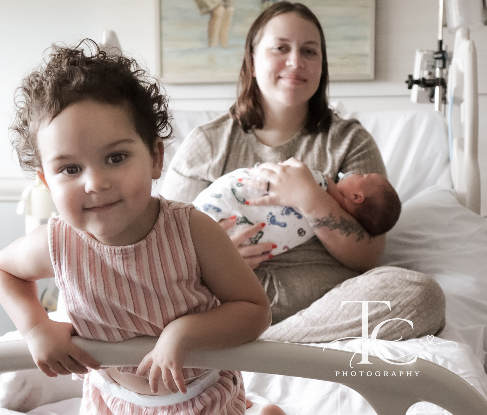 Older sibling smiling with mother and newborn behind her