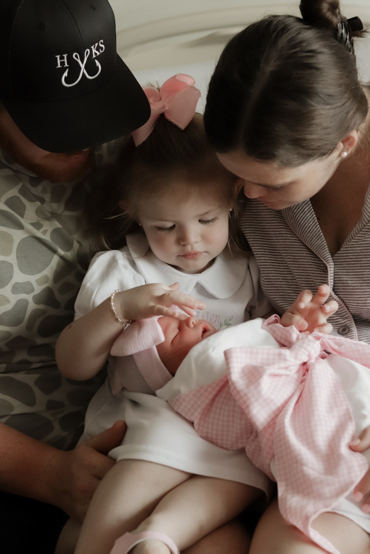 Parents and older sister admiring their newborn together