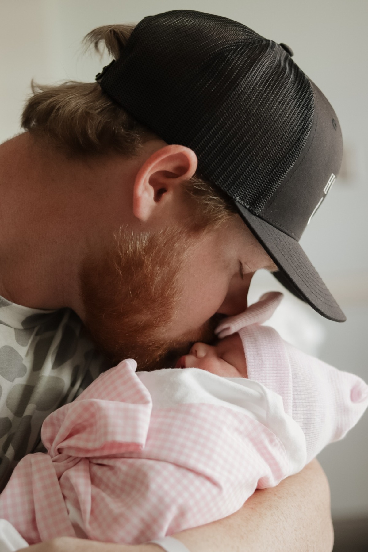 Father kissing his newborn held against his chest