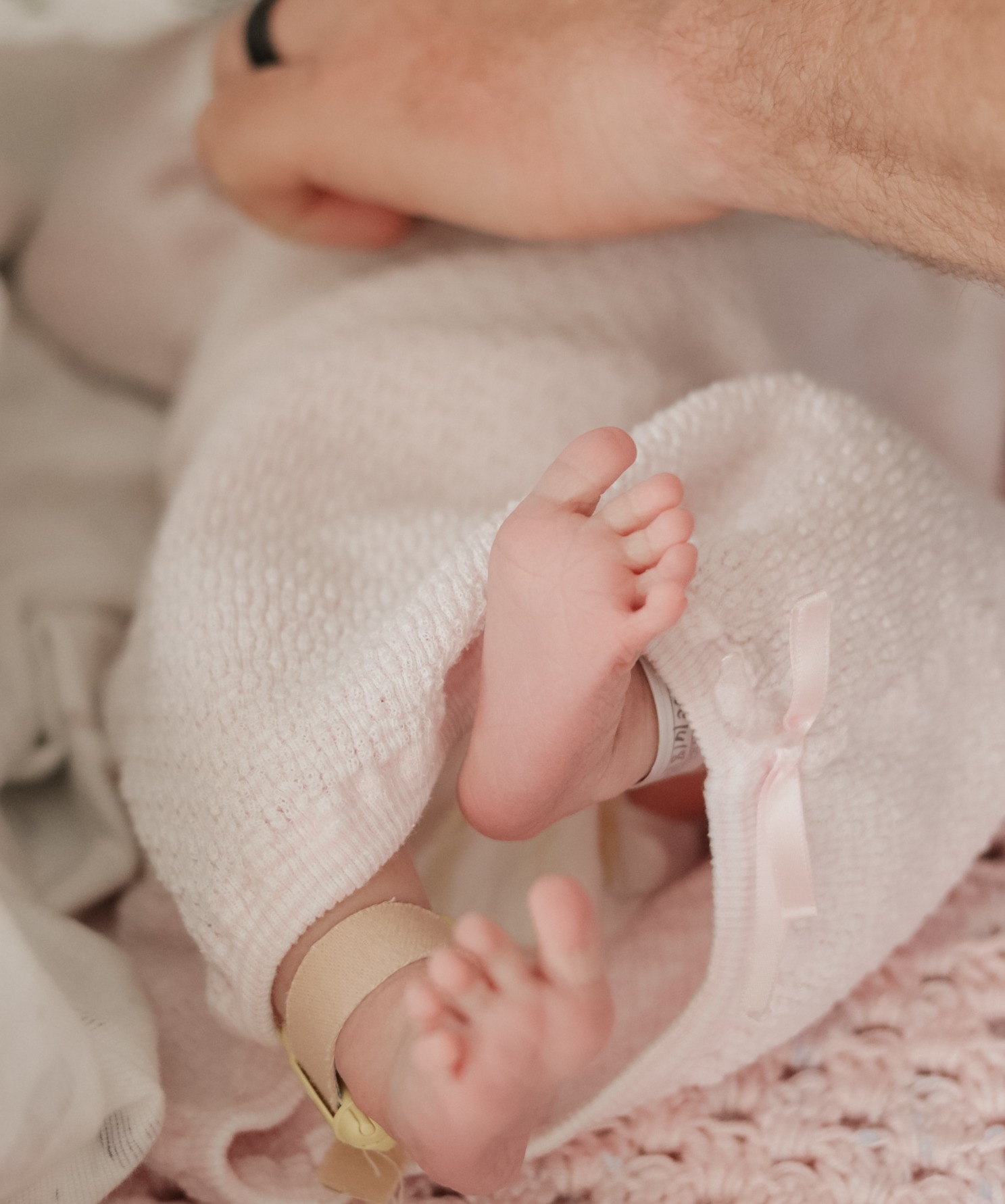 Tiny newborn toes peeking from a pink blanket