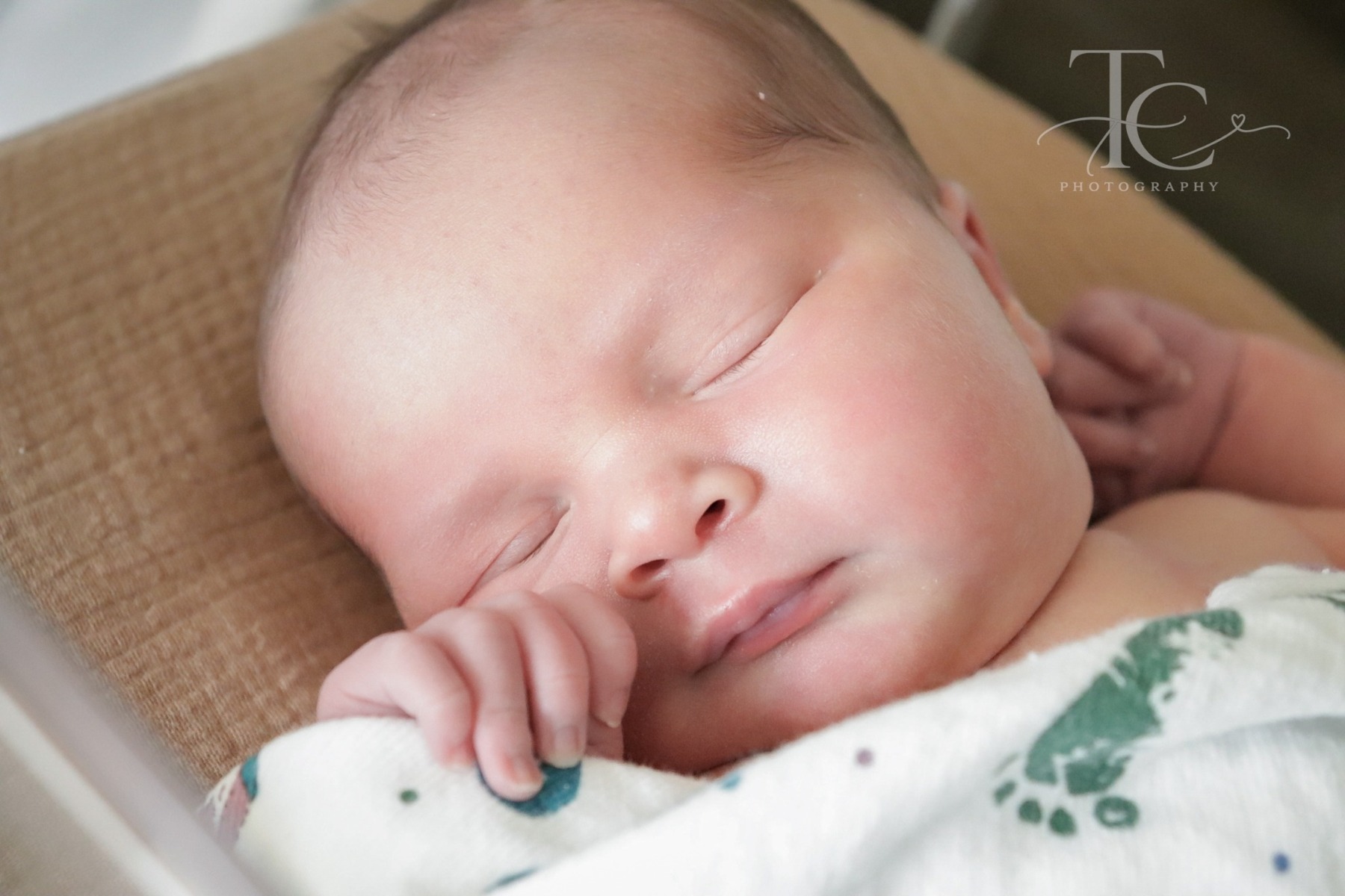 Close-up of a sleeping newborn with a hand beside their cheek
