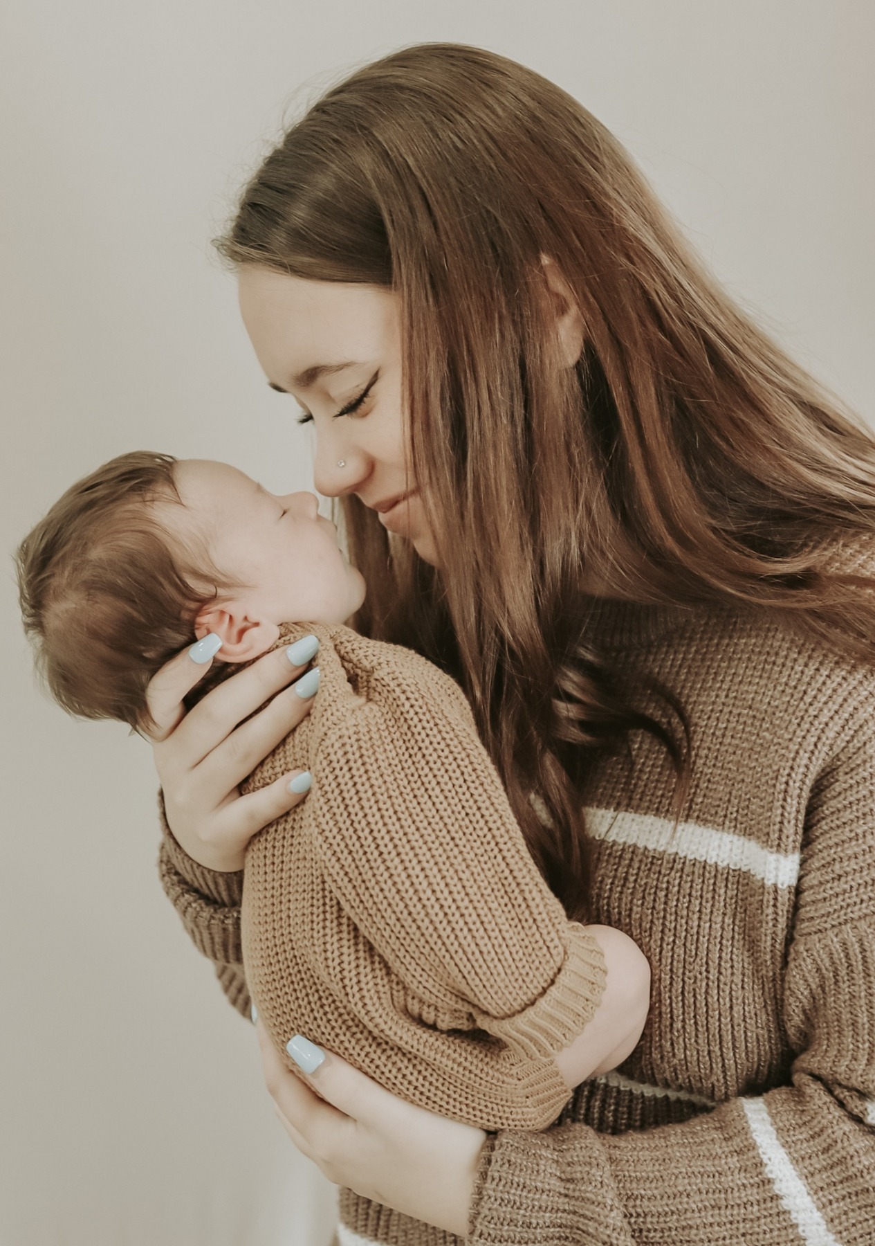 Mother kissing her newborn held close to her face