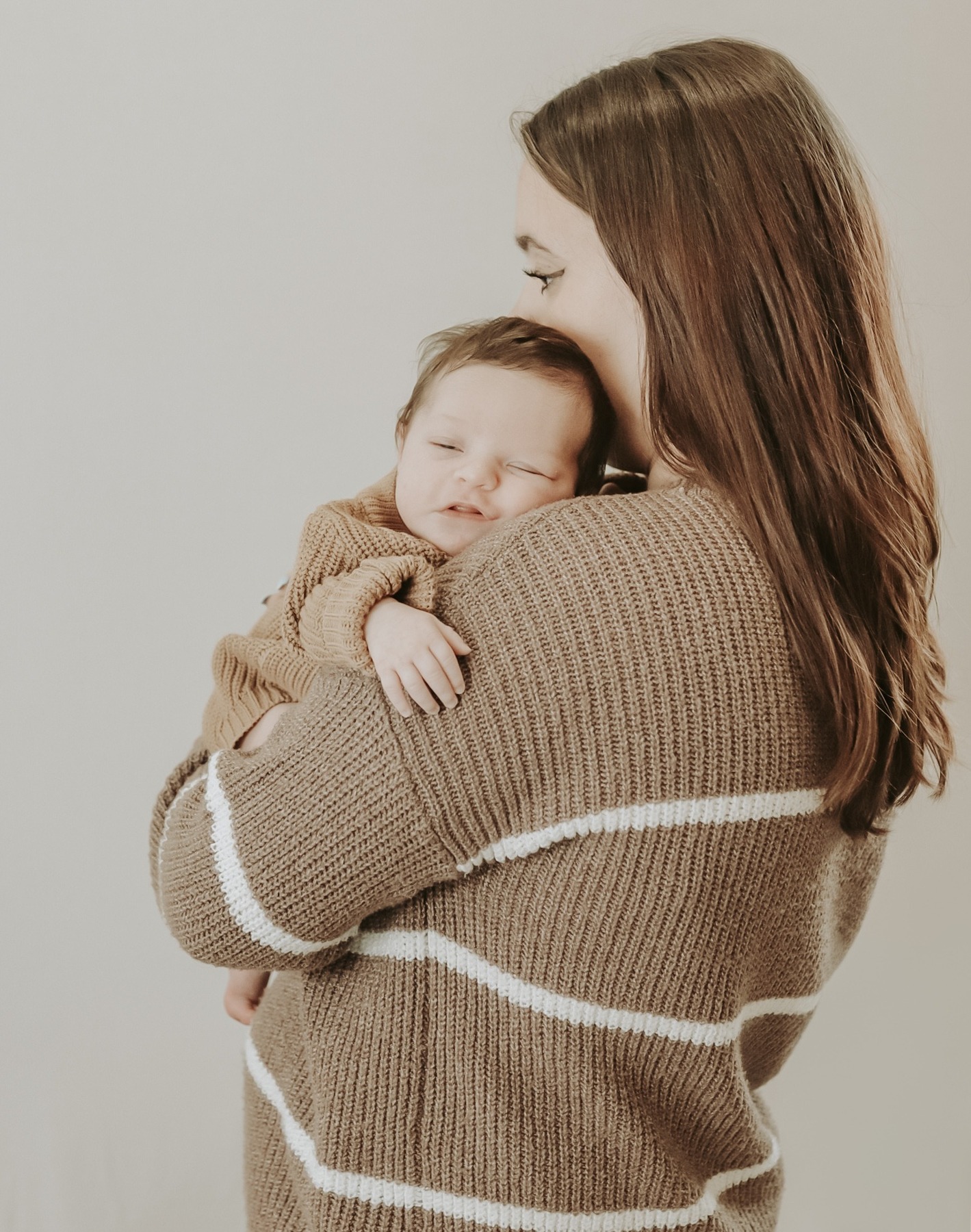 Mother cradling her sleeping newborn against her shoulder