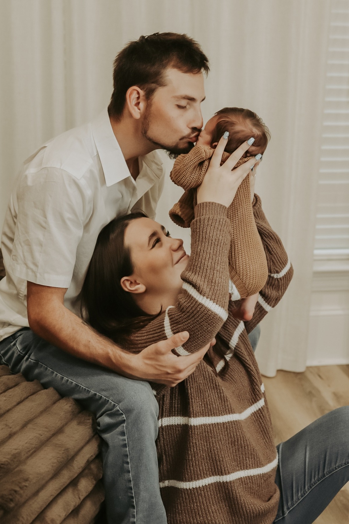 Parents cuddling and kissing their newborn together