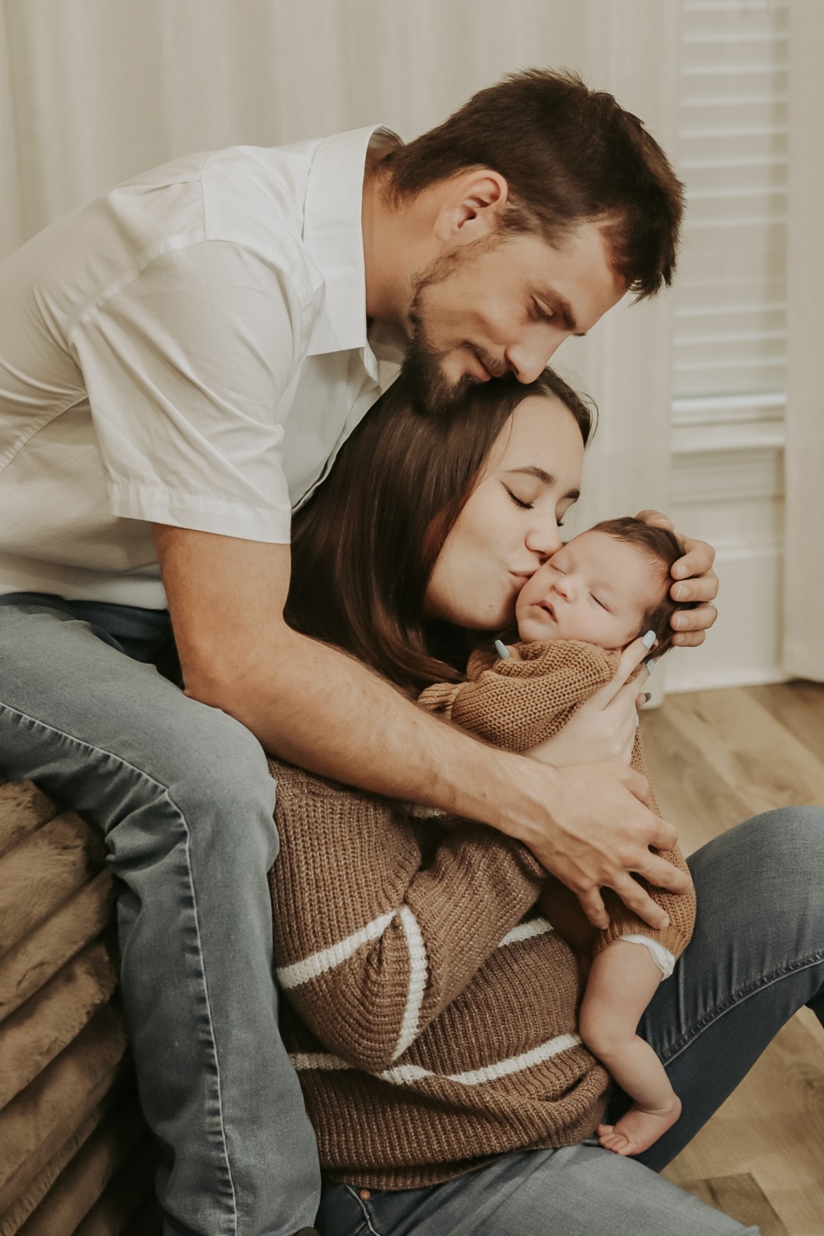 Father leaning over mother and newborn on a bed