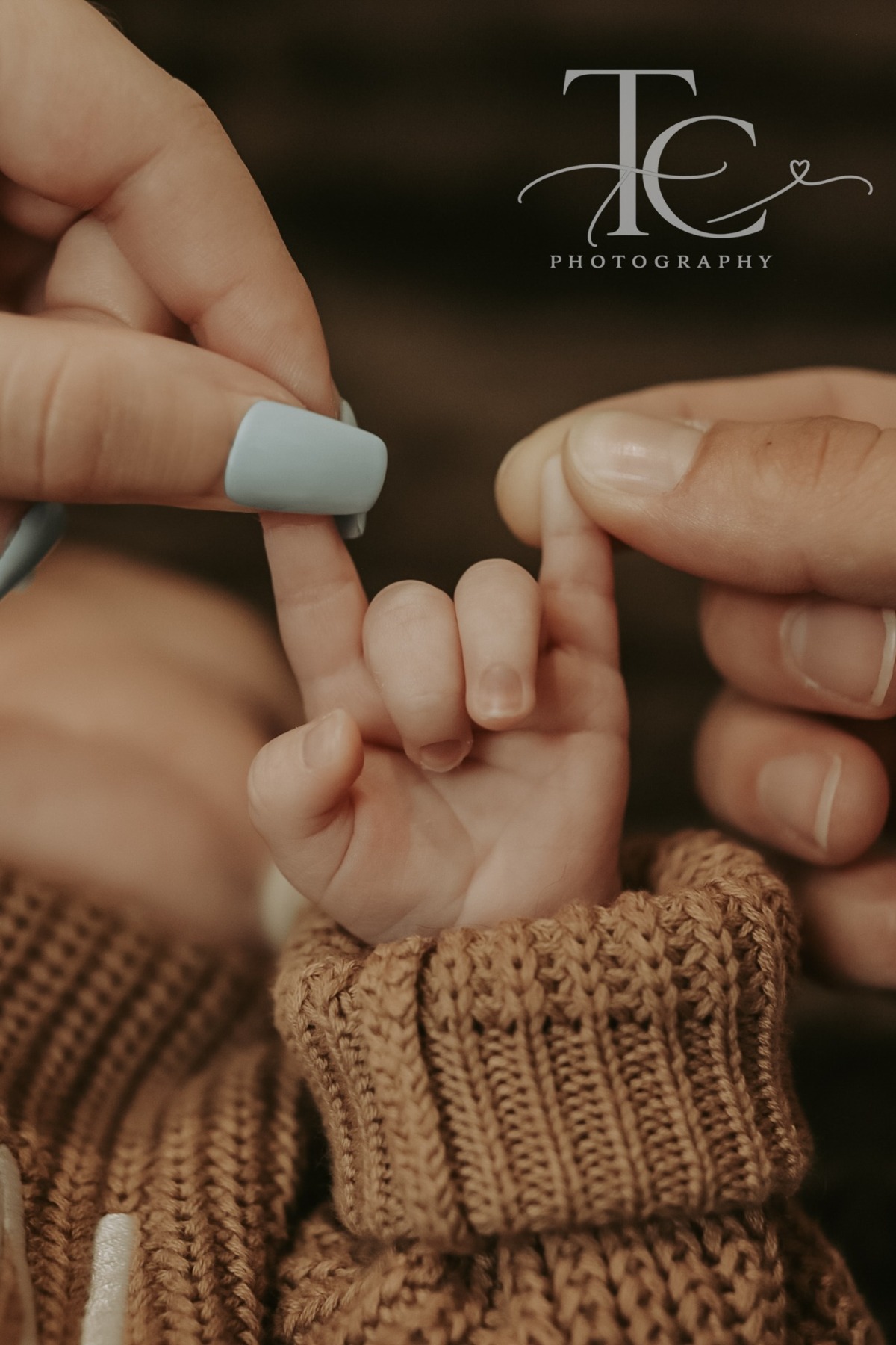 Tiny newborn fingers holding a parent’s finger