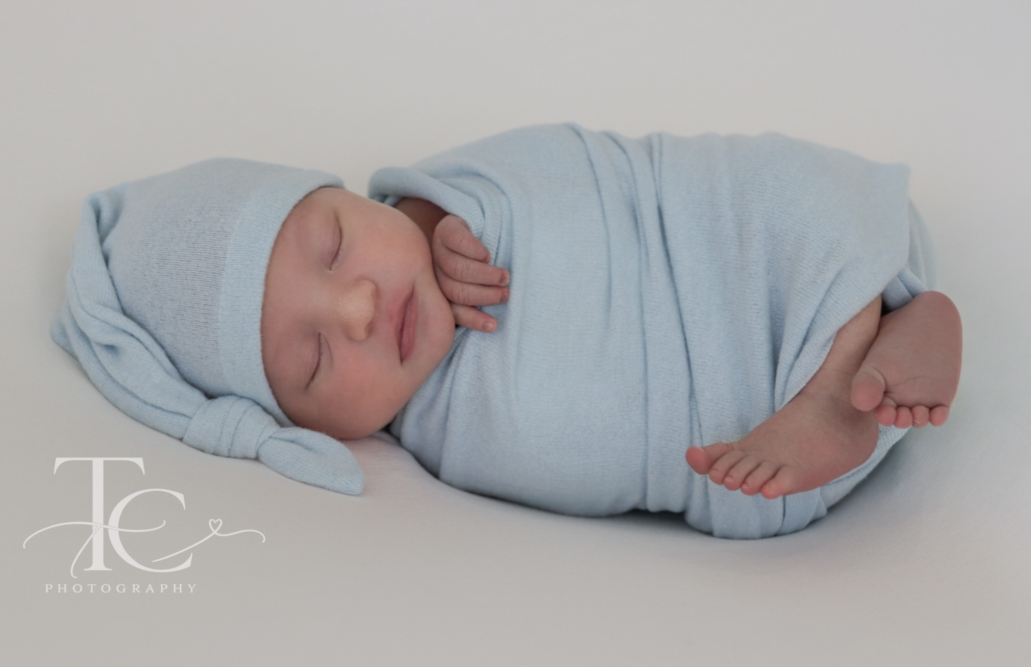Sleeping newborn wrapped in soft blue fabric