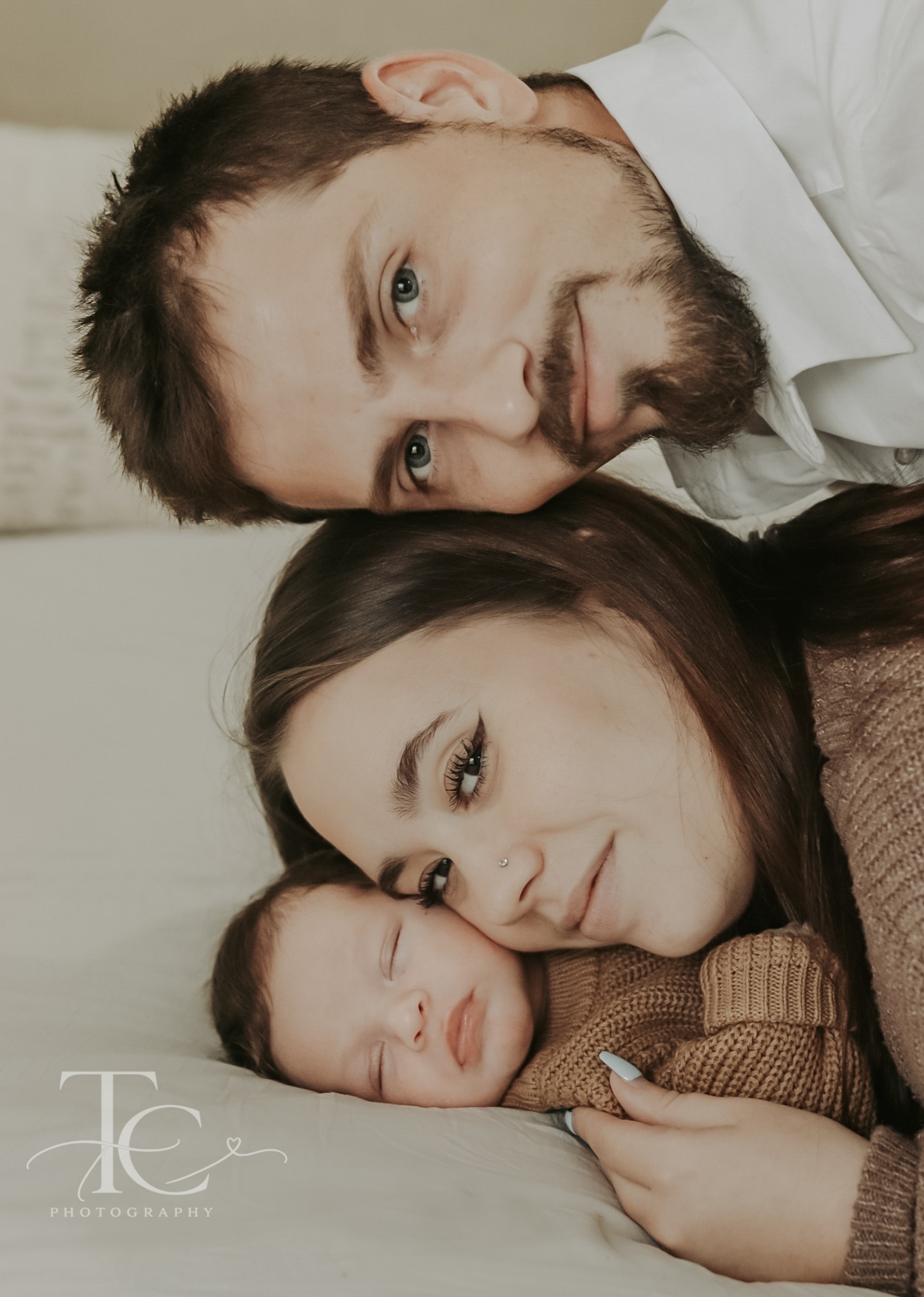 Sleeping newborn nestled in parents’ arms