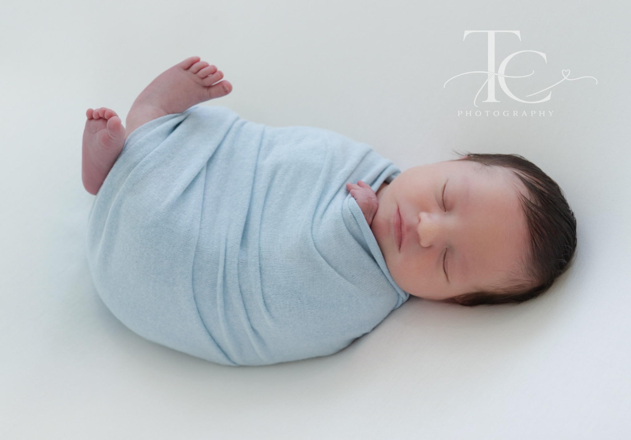 Wrapped newborn resting on a white backdrop
