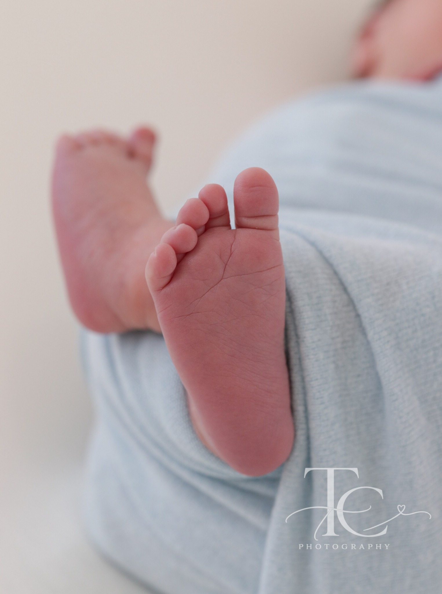 Close-up of newborn toes peeking out of a blue wrap