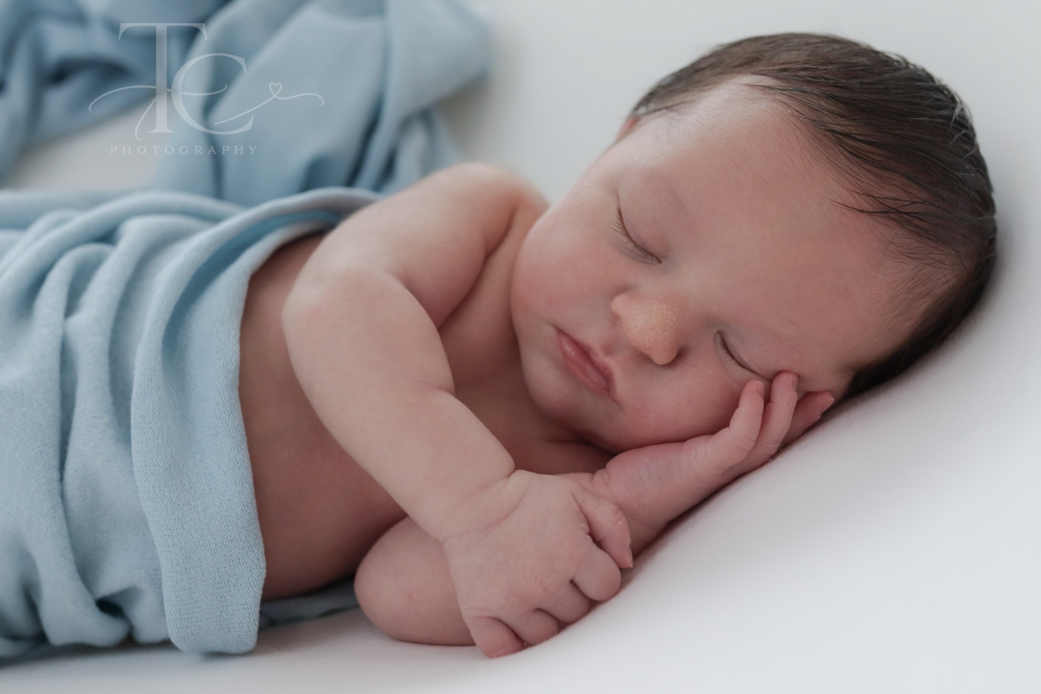 Close-up of a sleeping newborn with blue fabric