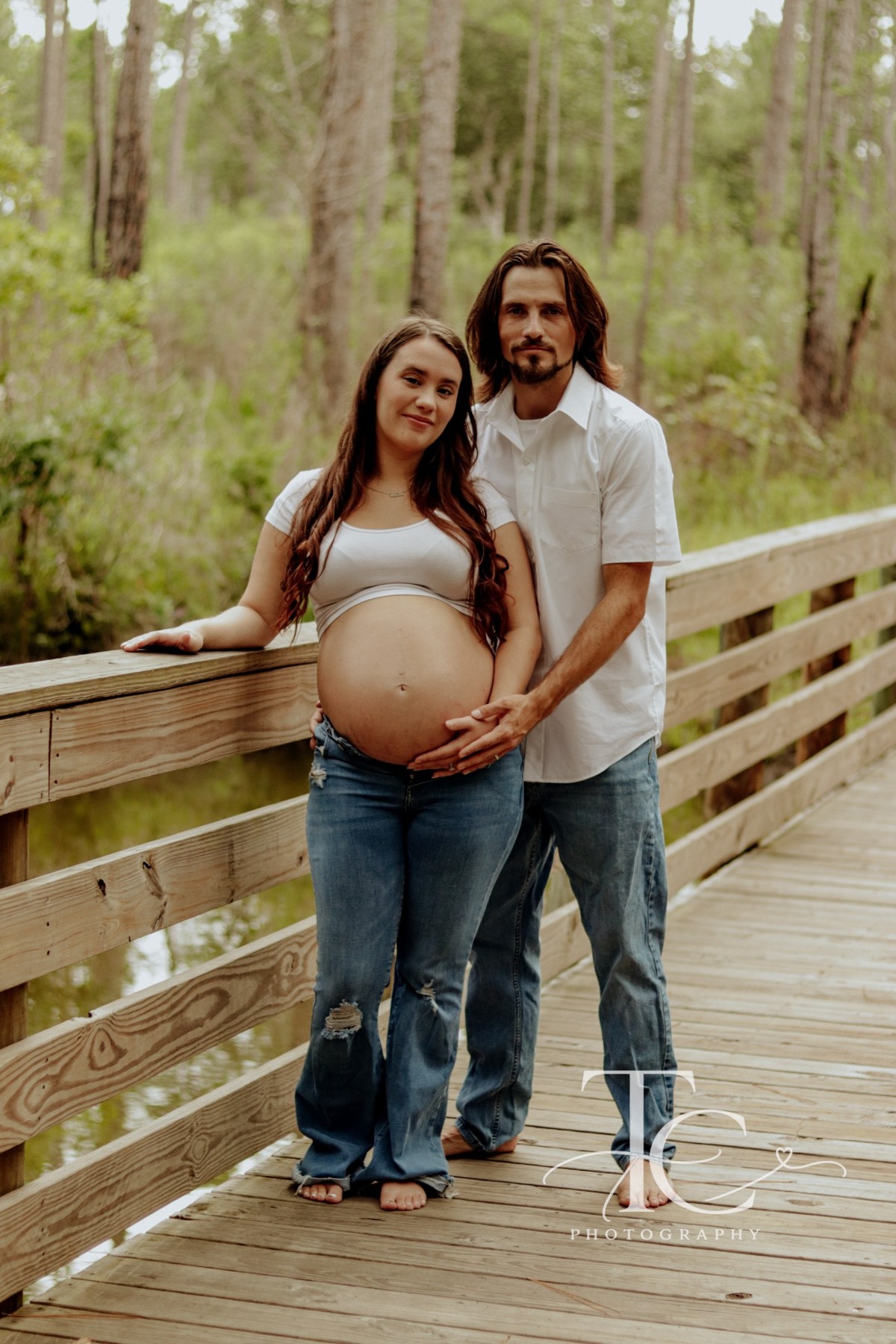 Expectant parents on a wooded boardwalk