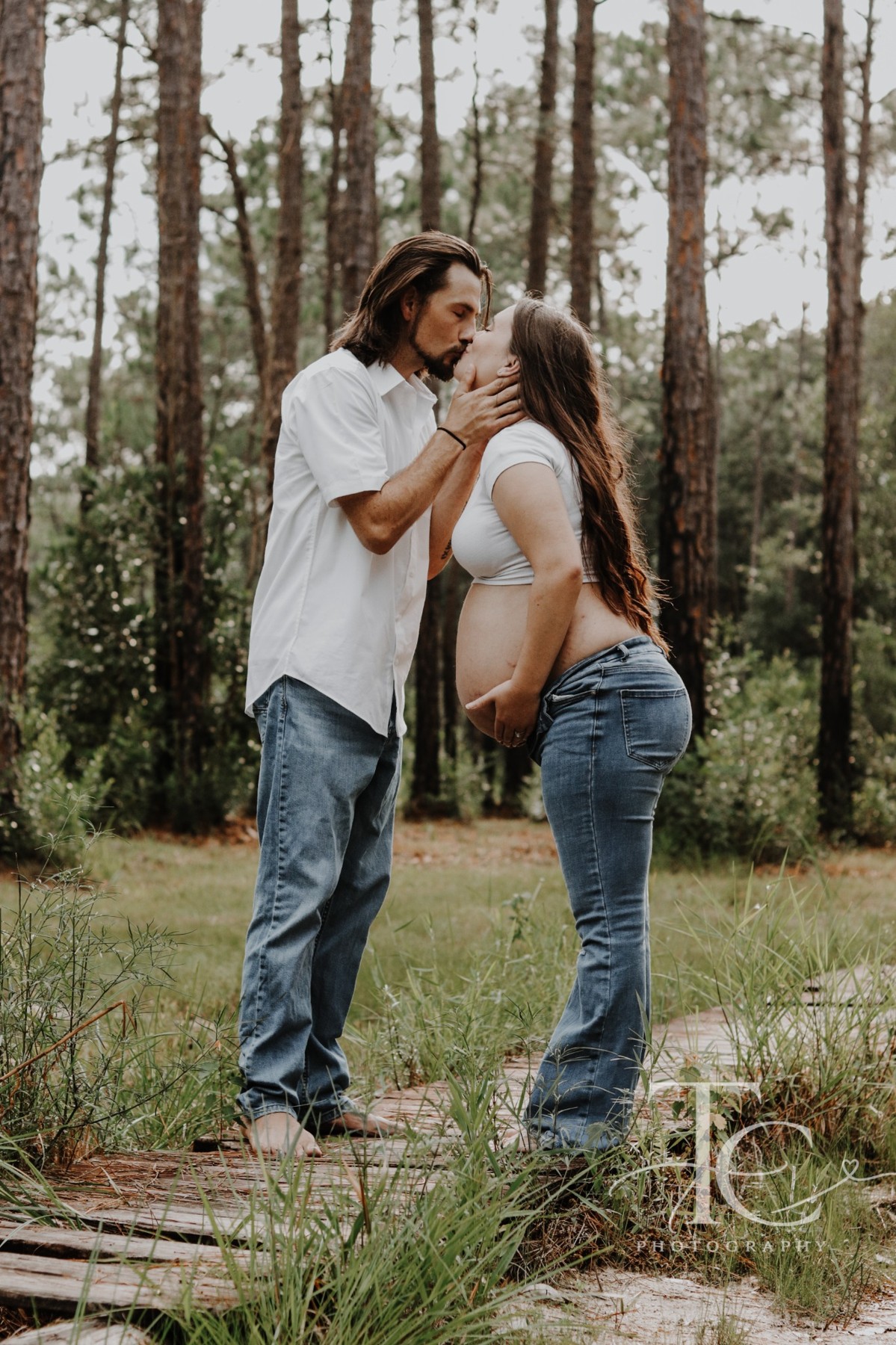 Couple sharing a kiss in a wooded setting