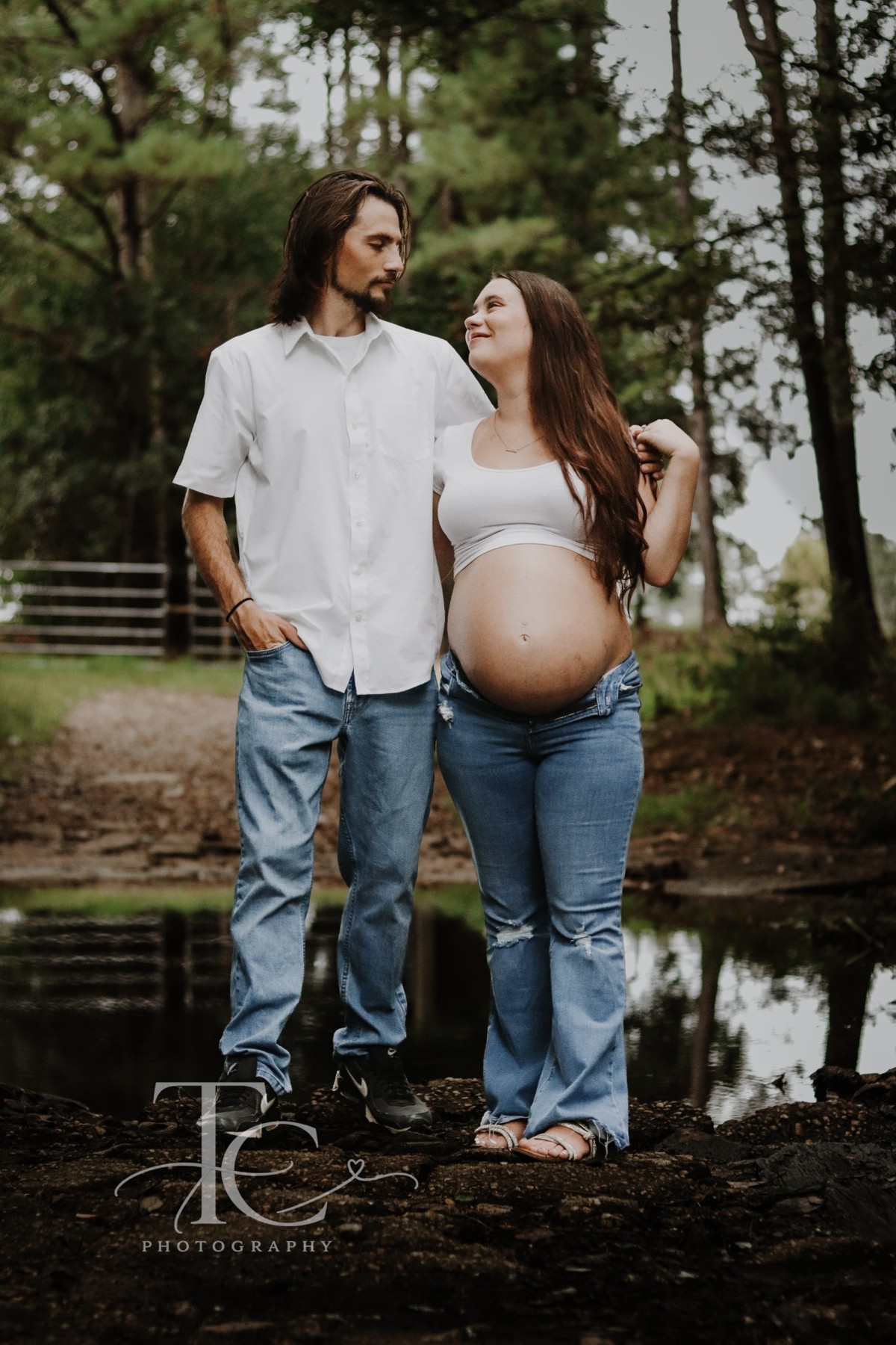 Expectant parents beside a pond in the woods
