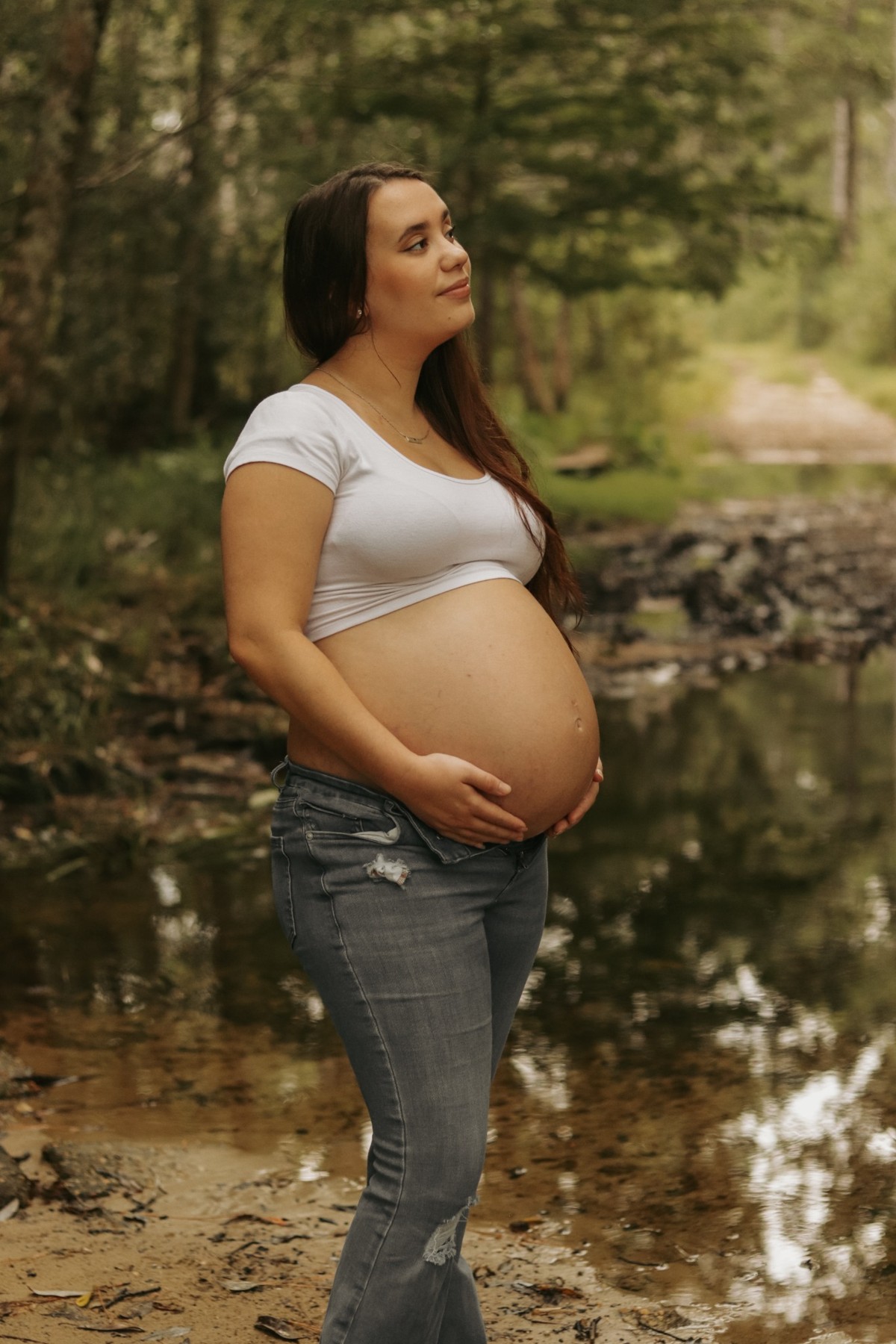 Expectant mother looking upward beside a pond