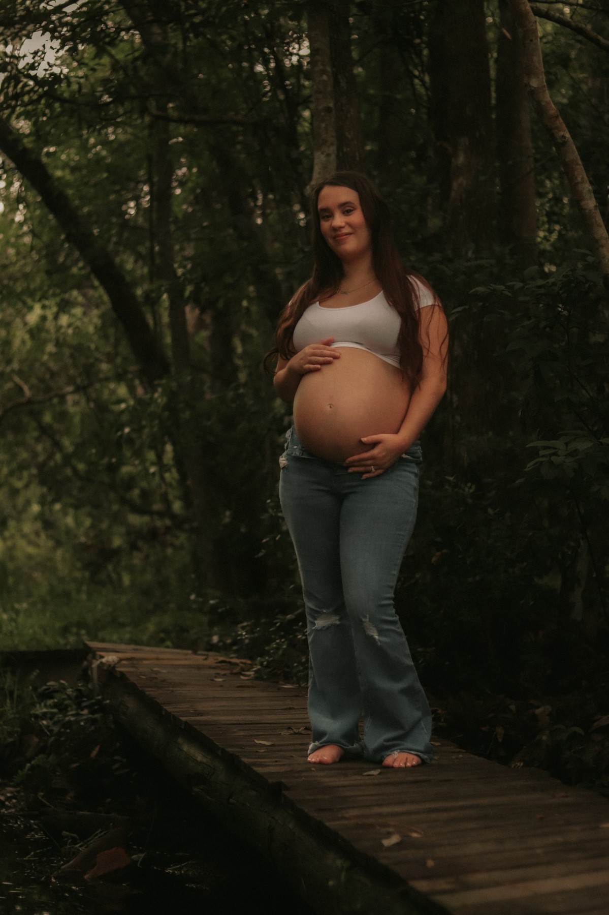 Expectant mother posing on a wooden walkway