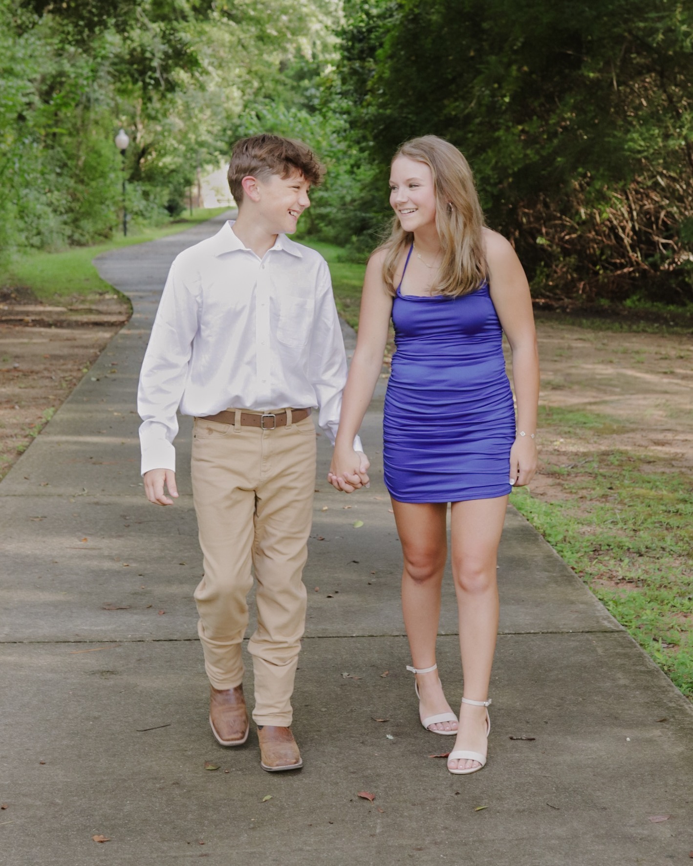 Teen couple walking together on a tree-lined path