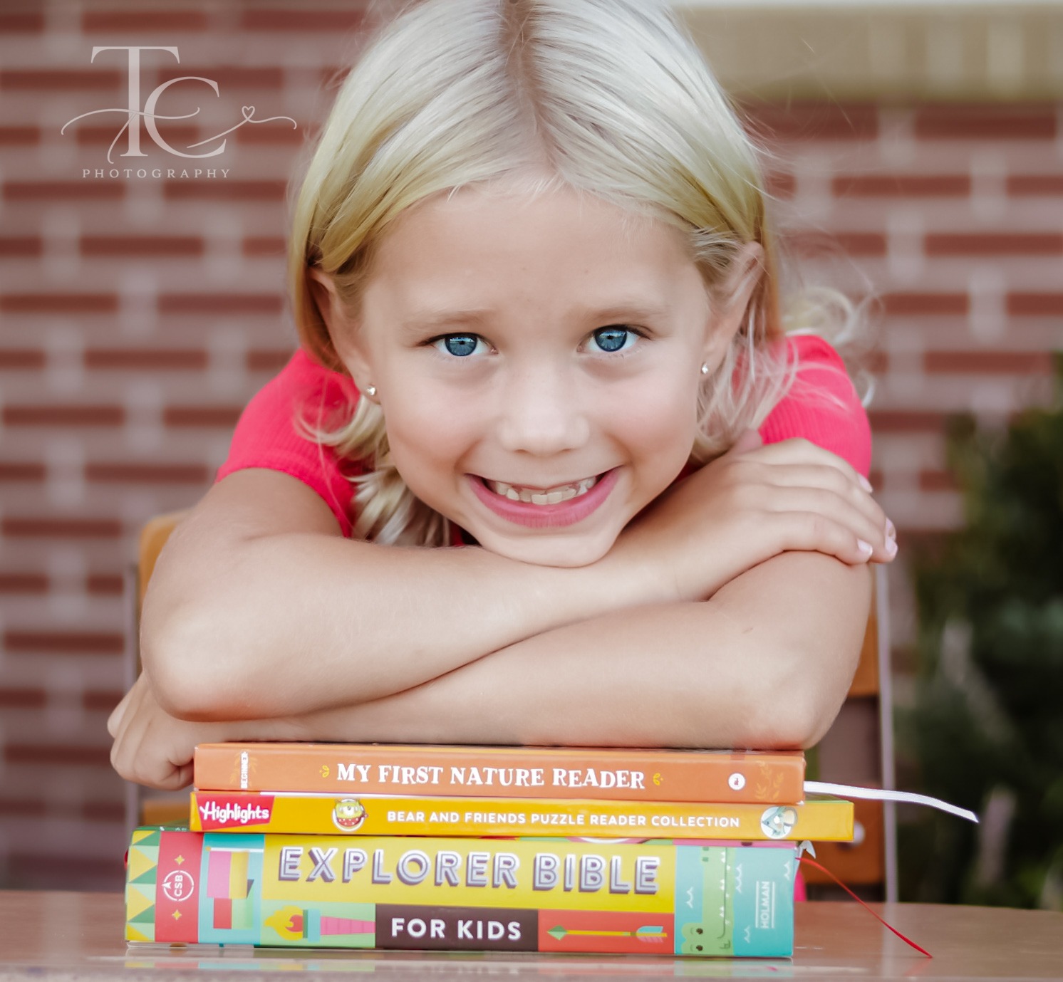 Smiling girl resting her arms on a stack of school books
