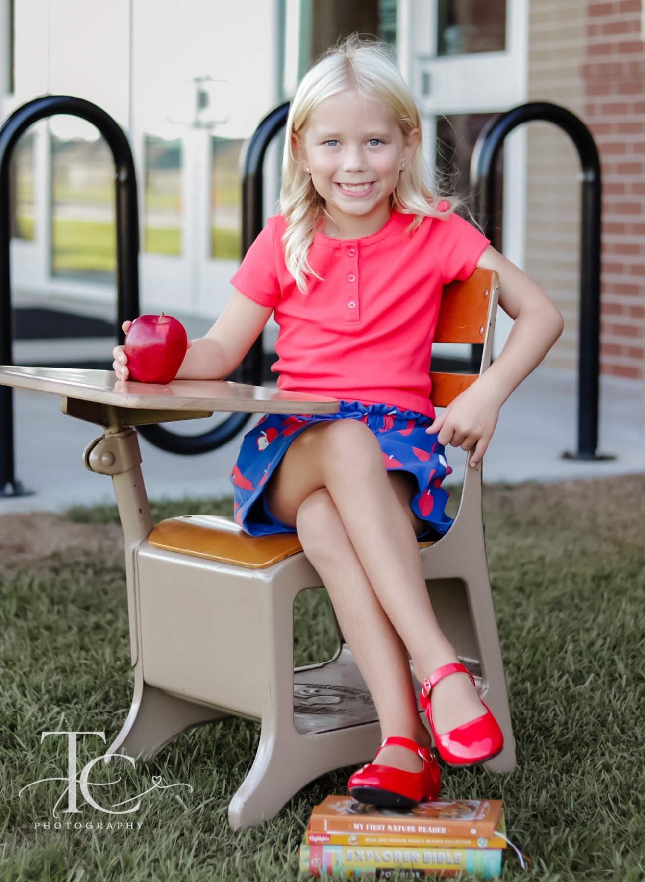 Girl seated at a school desk with a red apple