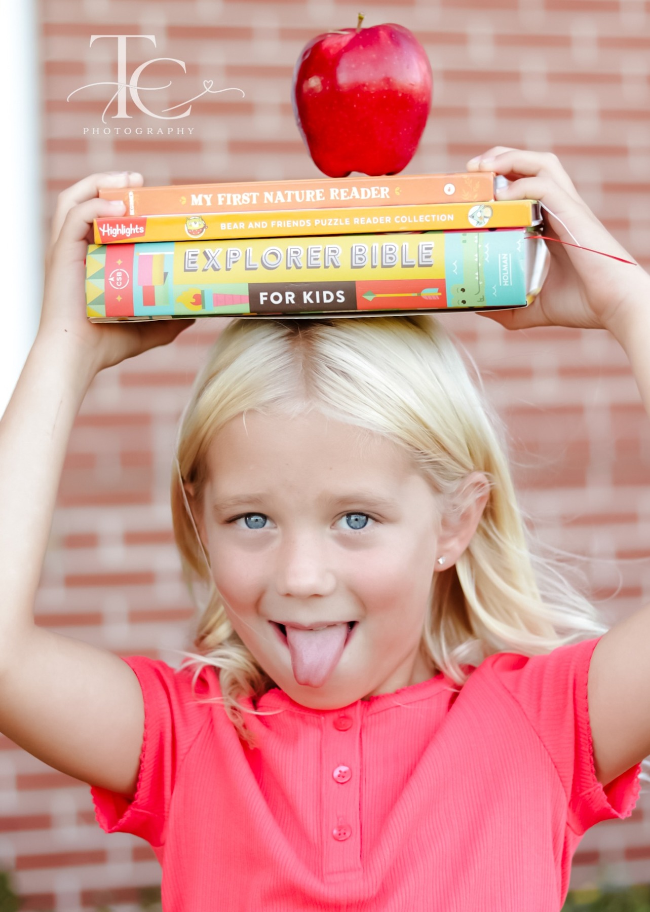 Girl balancing books and an apple above her head