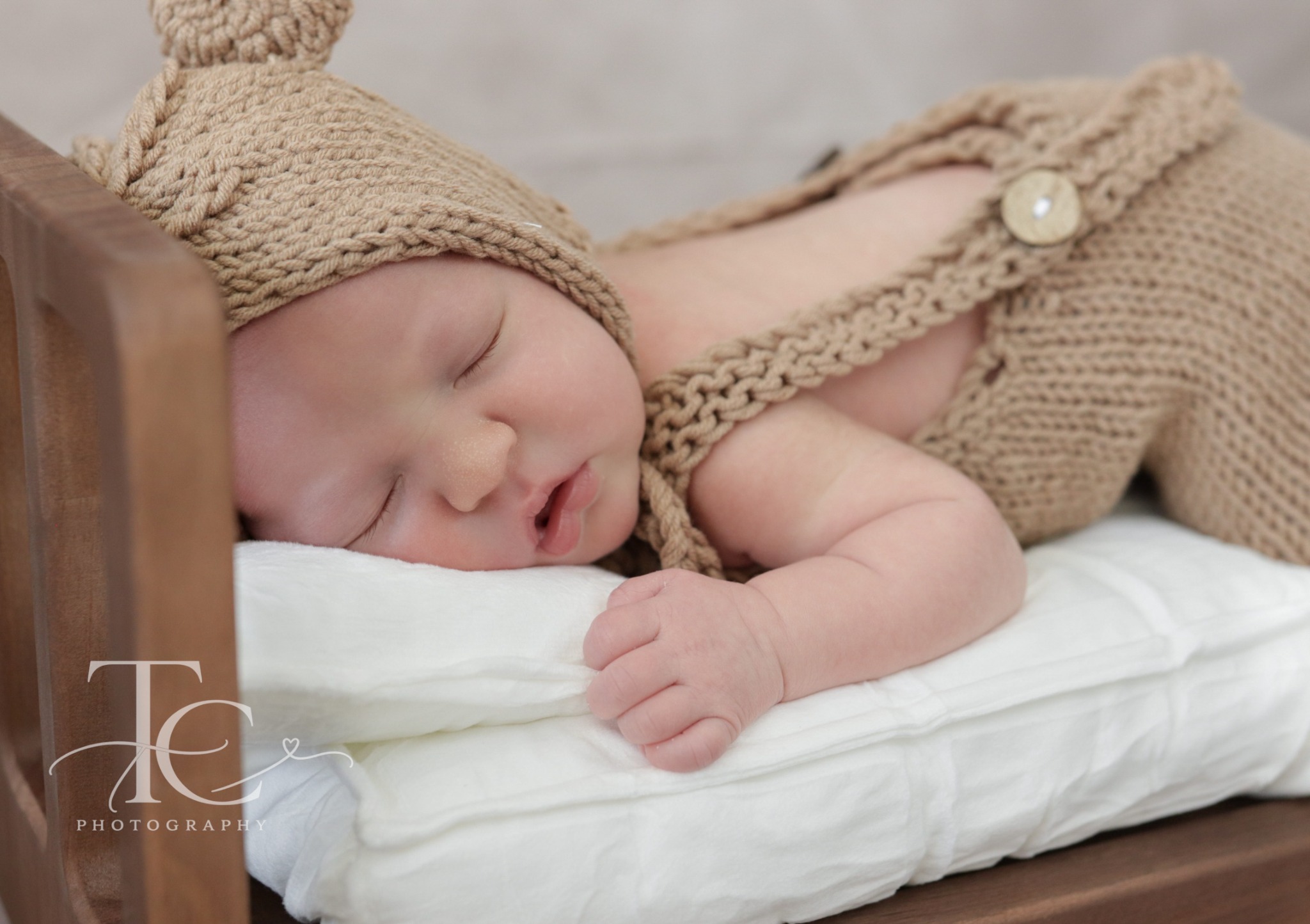 Close-up of newborn sleeping in a miniature wooden bed